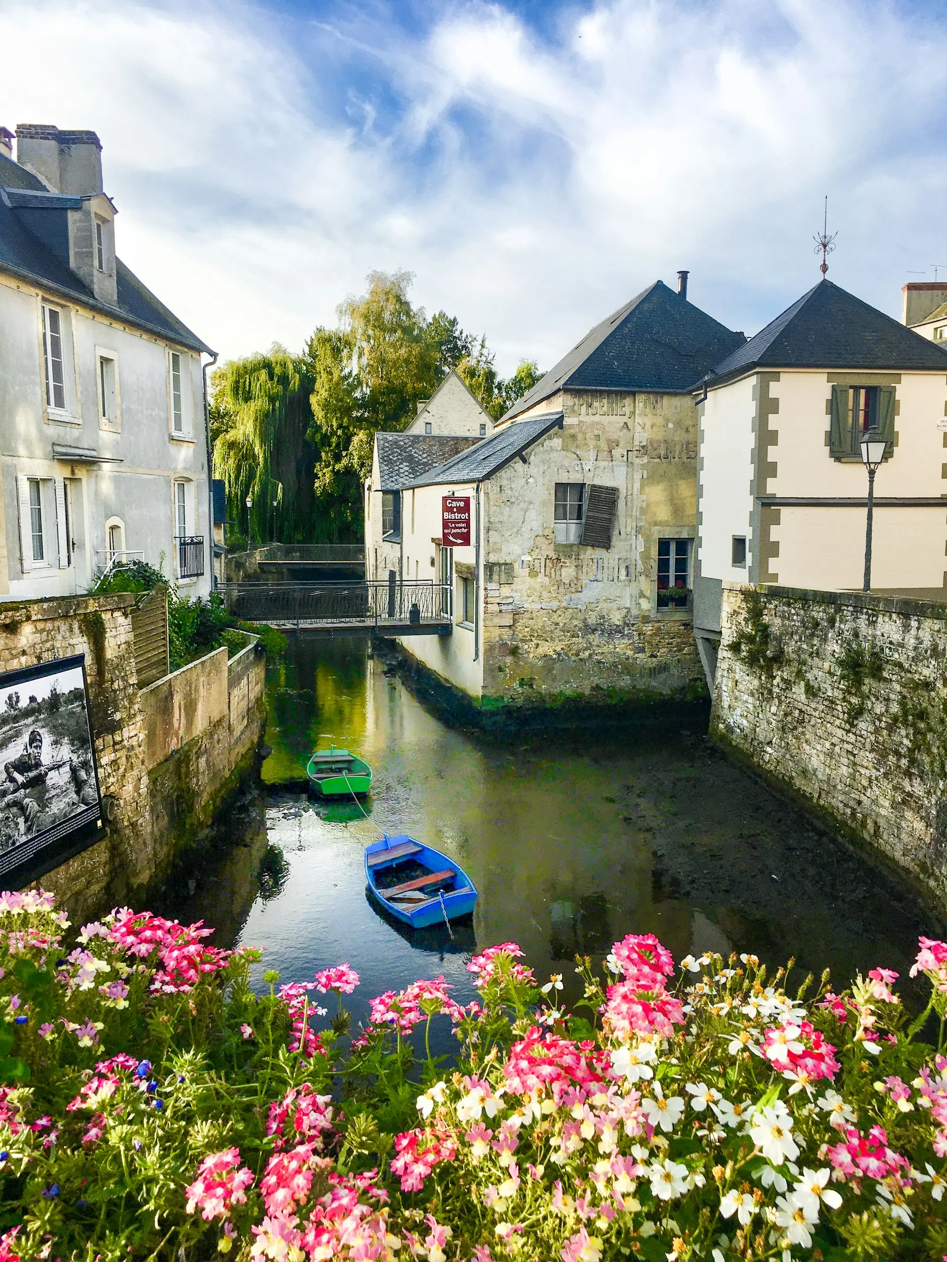 A flower-lined canal in the old Norman market town with small boats in Bayeux