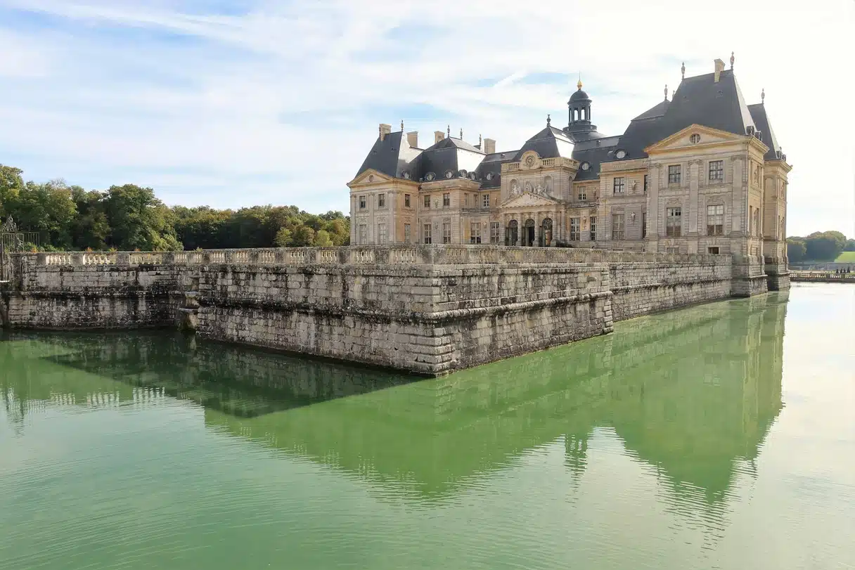 The Château de Vaux-le-Vicomte and its stone terrace reflected in the green water of the moat