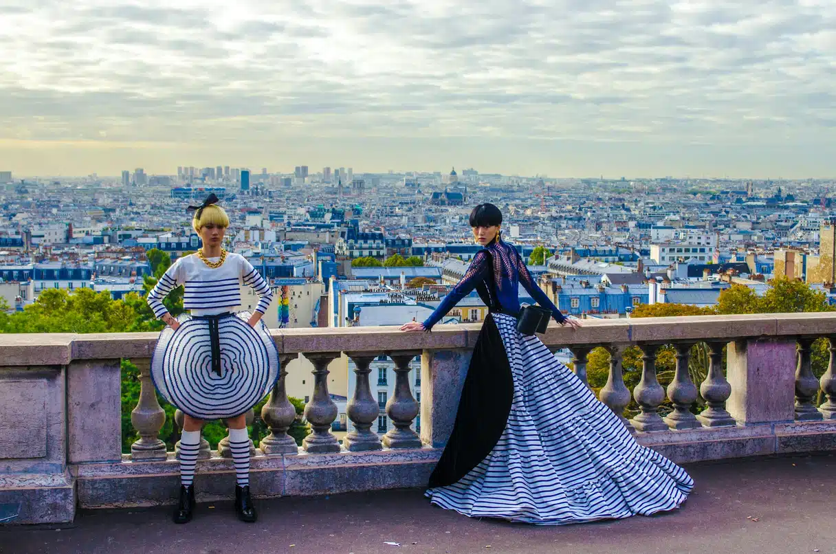 Des invités à la tenue extravagante pendant la Fashion Week de Paris, avec une vue panoramique de Paris en arrière-plan