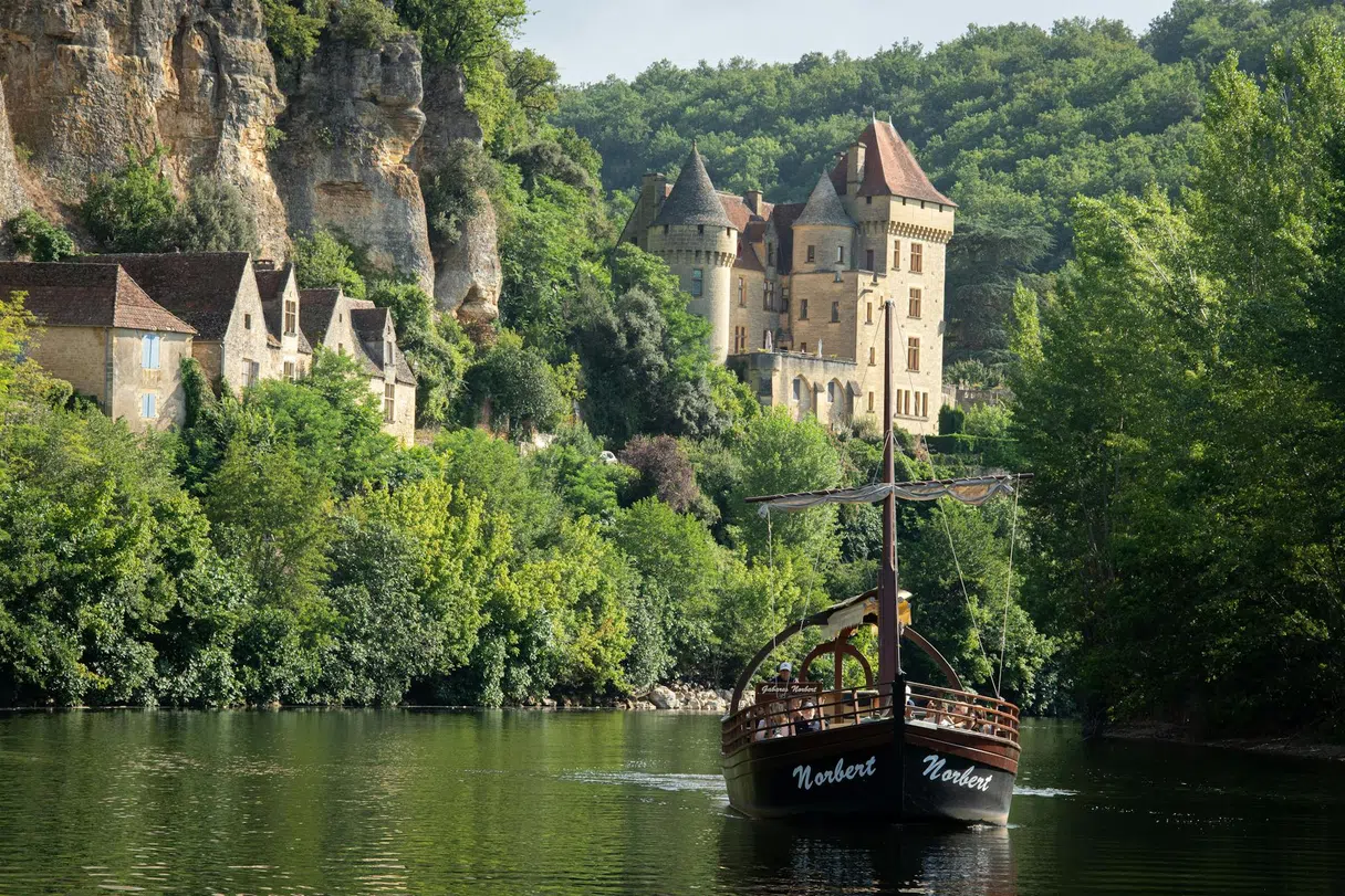 Une gabare traditionnelle sur la Dordogne avec un château en arrière-plan