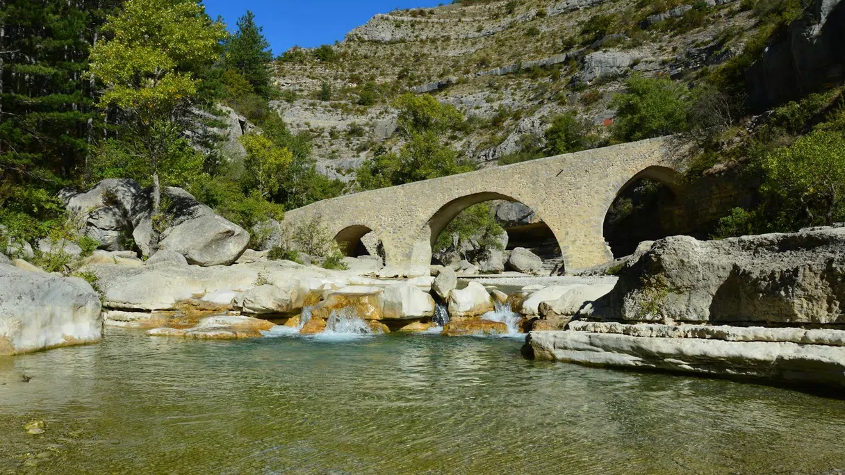 Un pont en pierre au-dessus de l'eau claire dans les Gorges de la Méouge