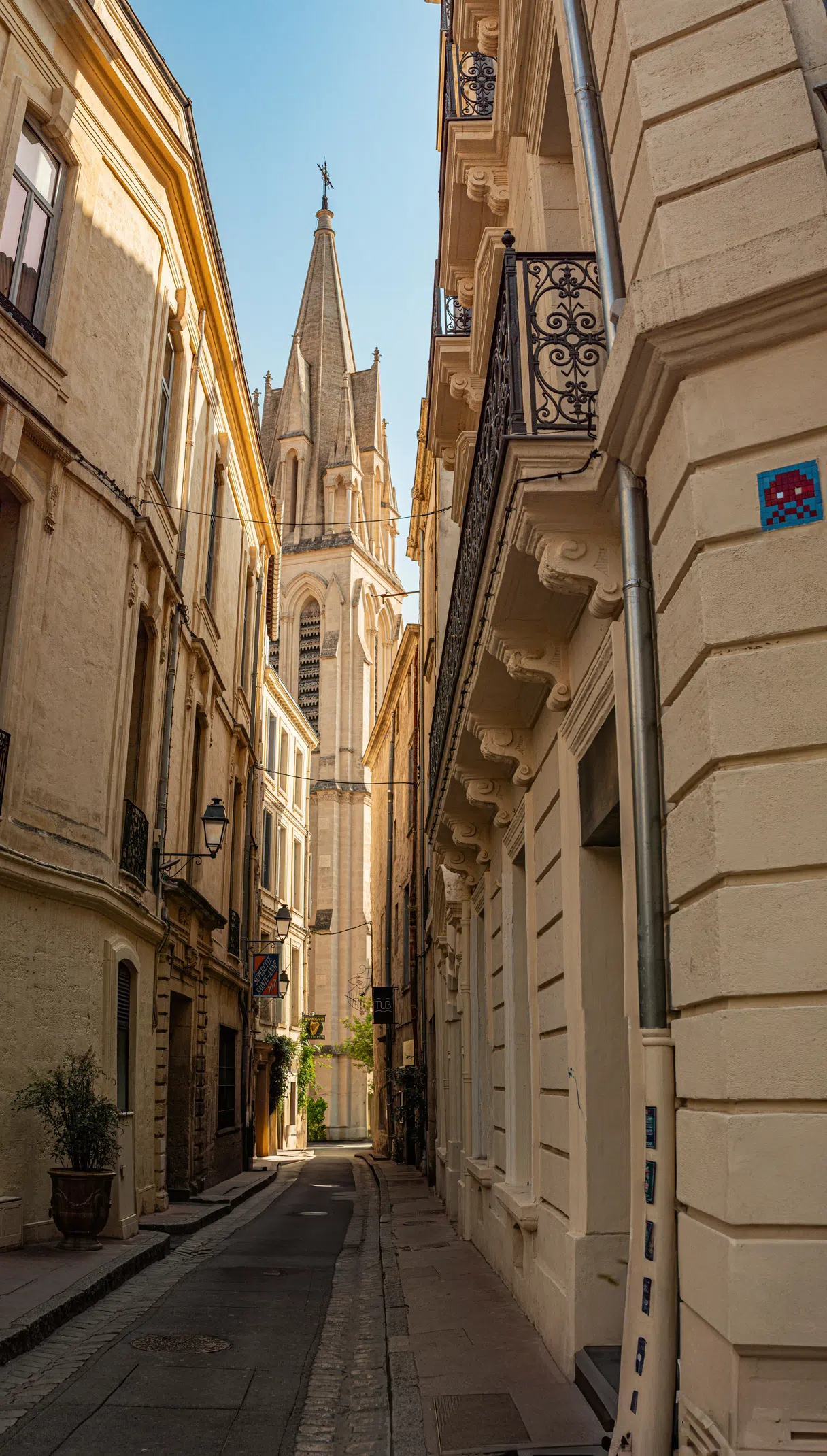 Une ruelle historique étroite à Montpellier avec un clocher en arrière-plan