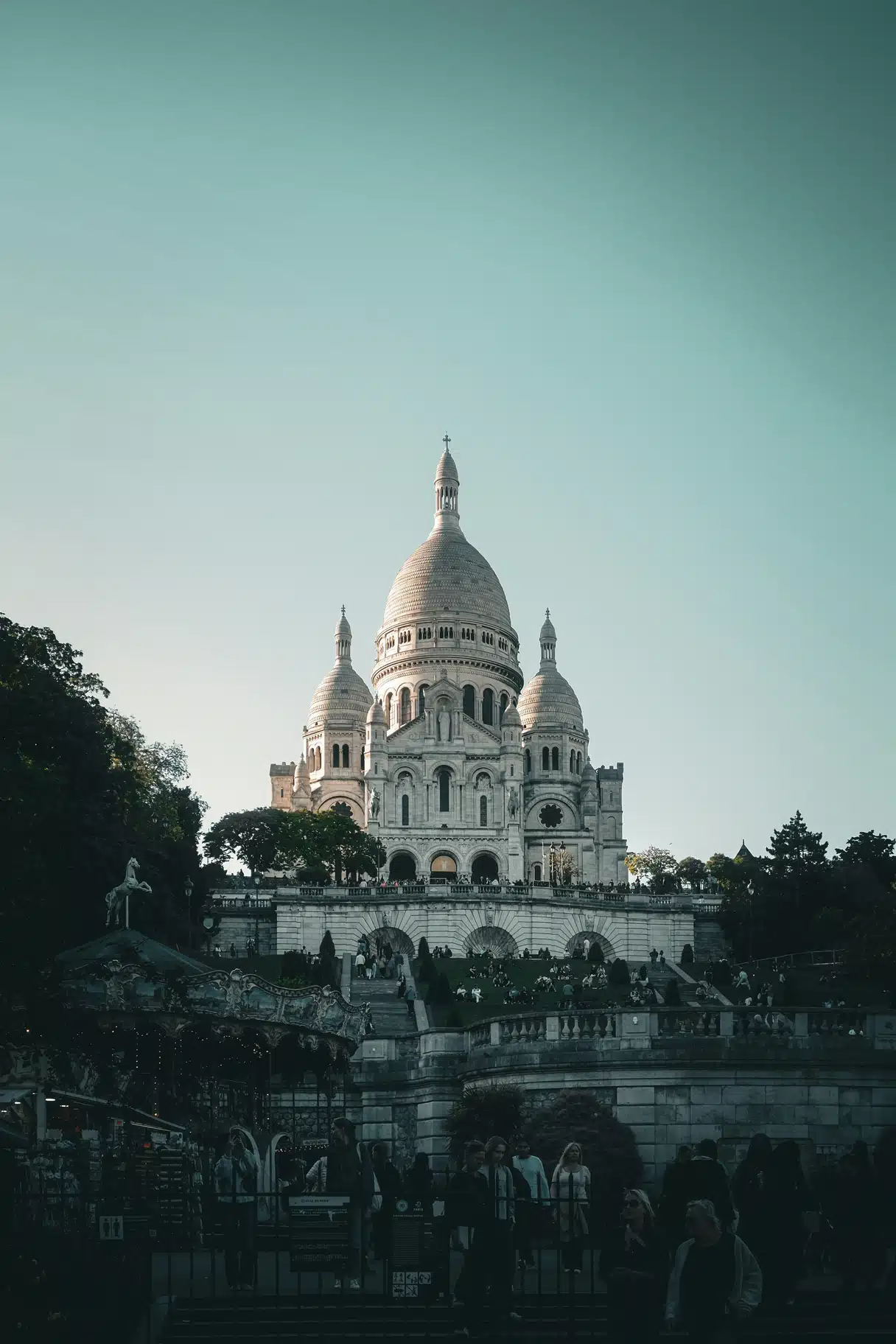 The Sacré-Cœur basilica above the carousel and terraced steps of Montmartre in Paris at dusk