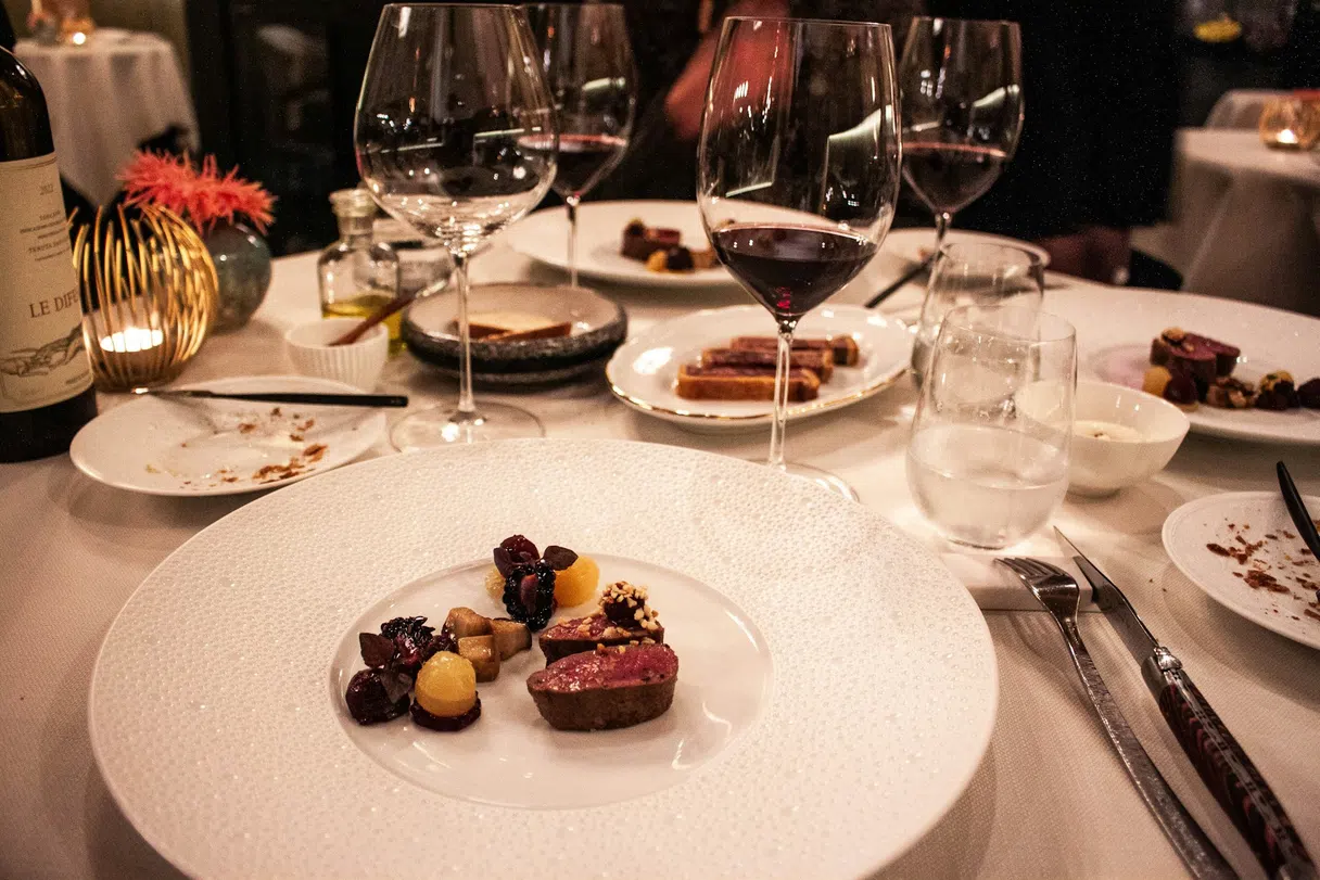 A set restaurant table with a plated dish and a glass of wine