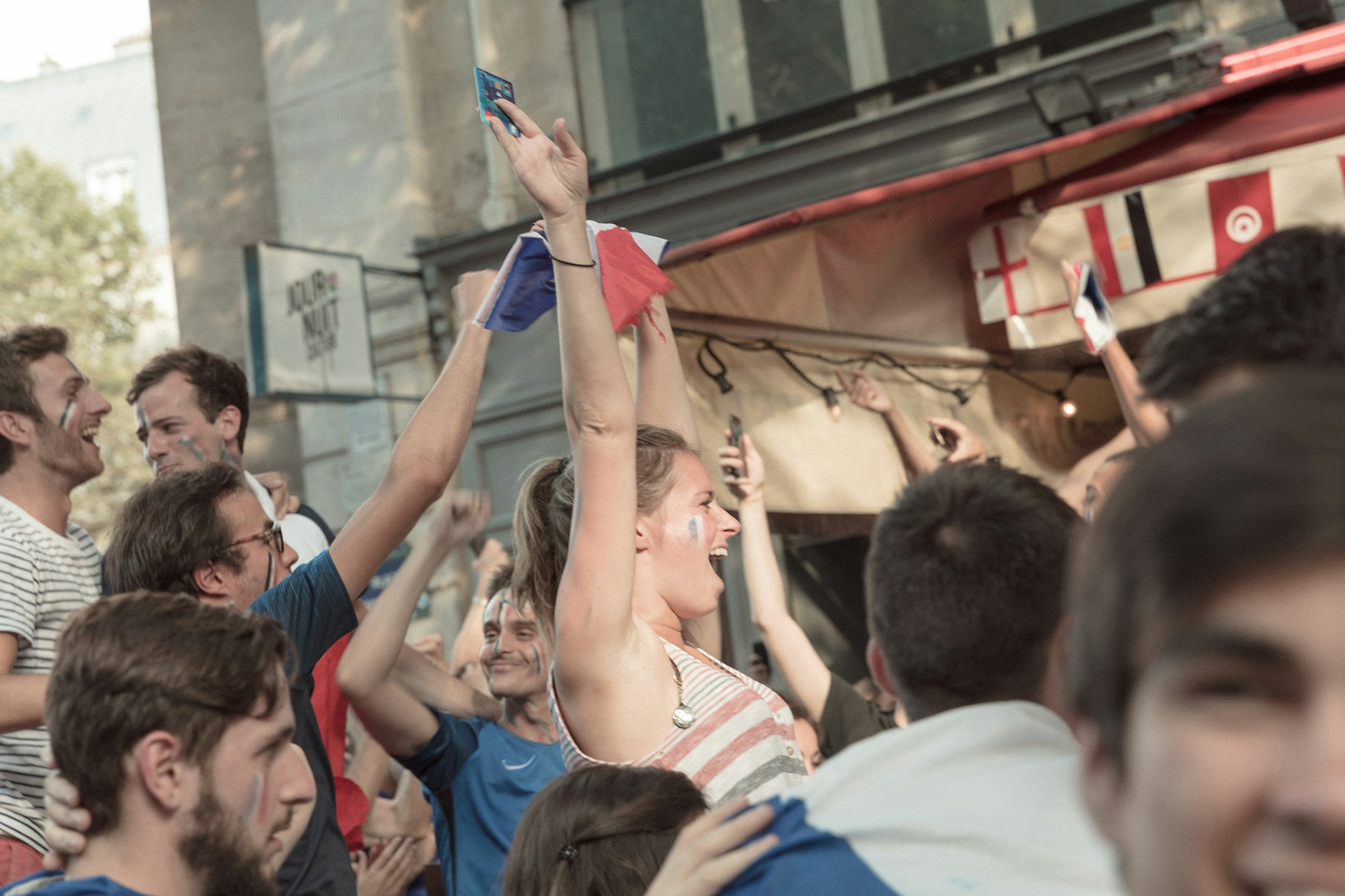 Des supporters de football regardant la Coupe du Monde 2026 en France sur un écran géant dans un bar de ville animé